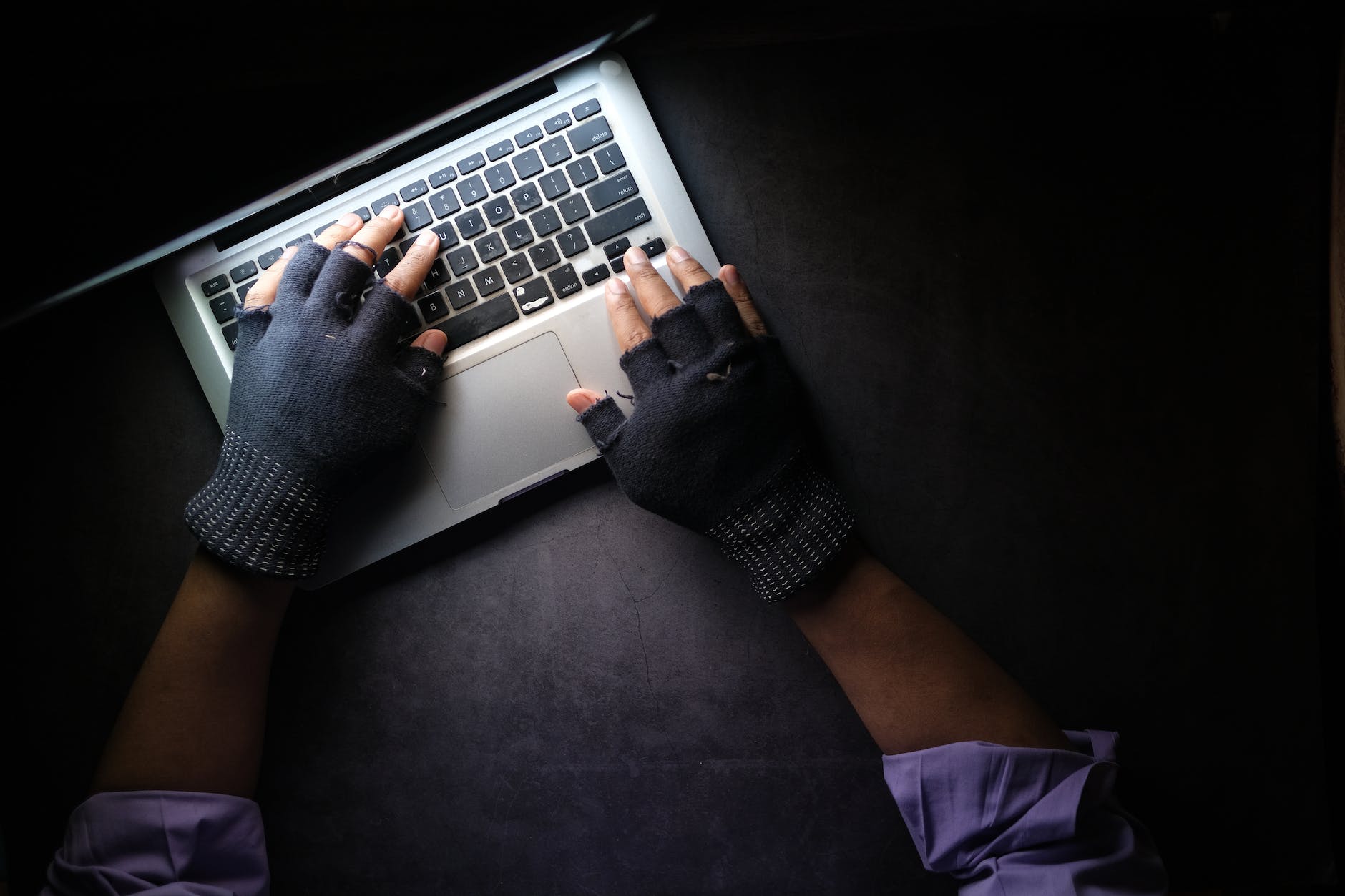 a person typing on laptop while wearing a fingerless gloves